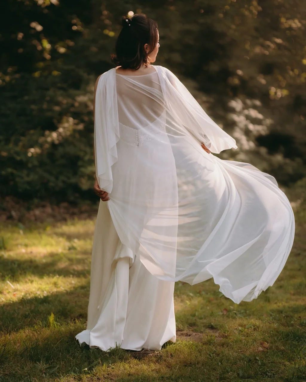 Braut dreht sich auf einer Wiese, das leichte Kleid weht