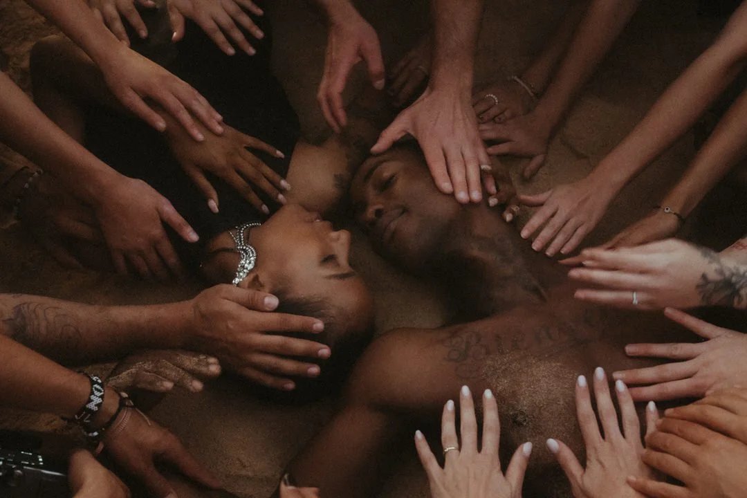 Brautpaar am Boden, umgeben von liebevoll ausgestreckten Gästehänden