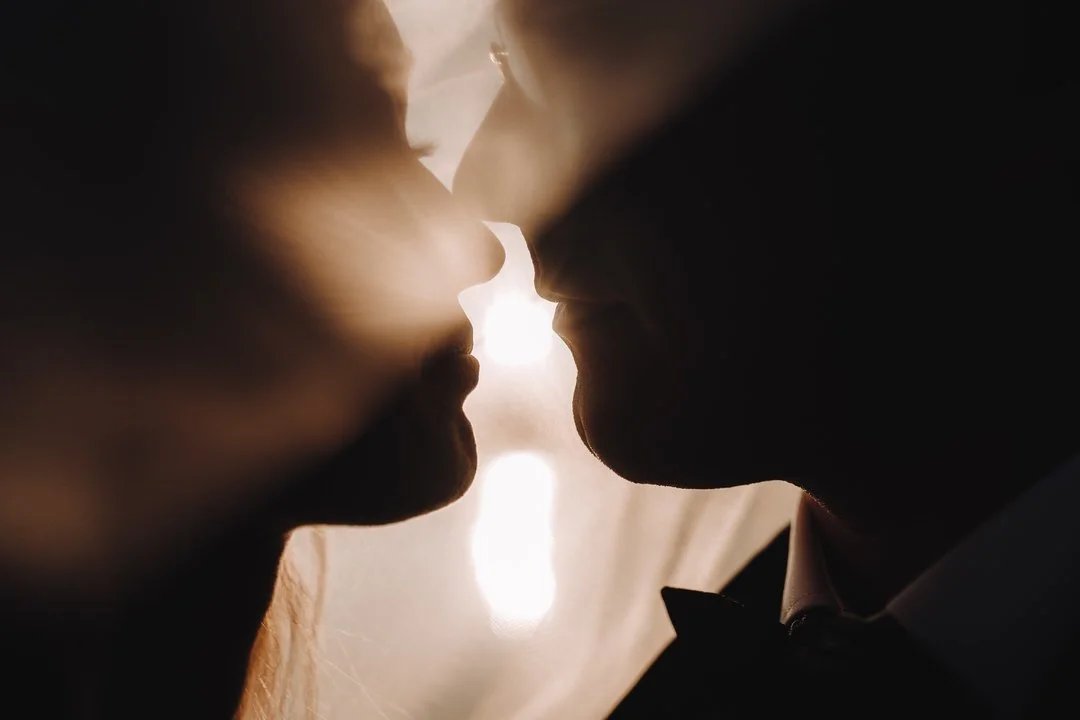 Silhouette eines Brautpaares kurz vor dem Kuss im dramatischen Gegenlicht