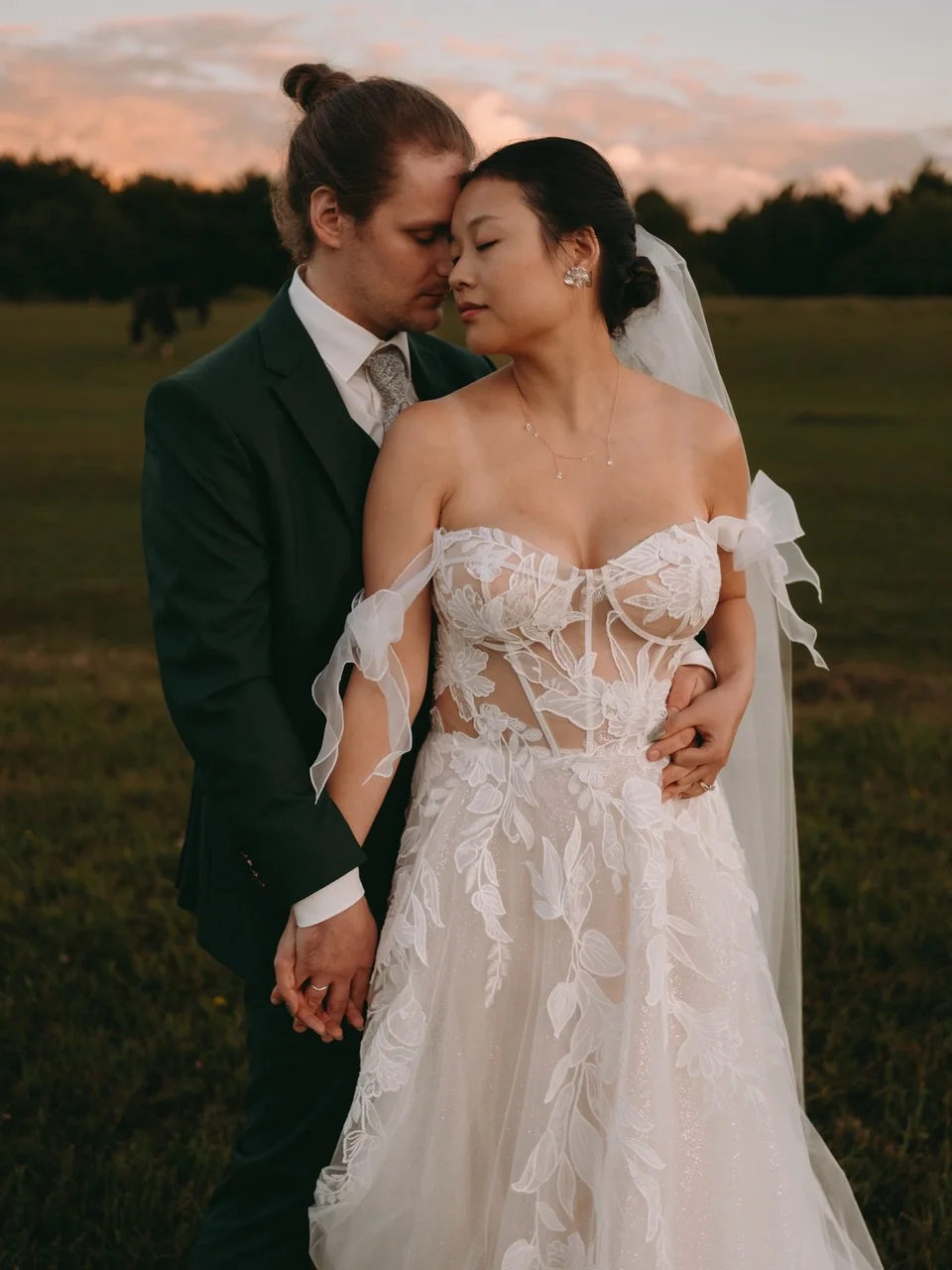 Bräutigam küsst Braut auf die Schläfe im Abendlicht