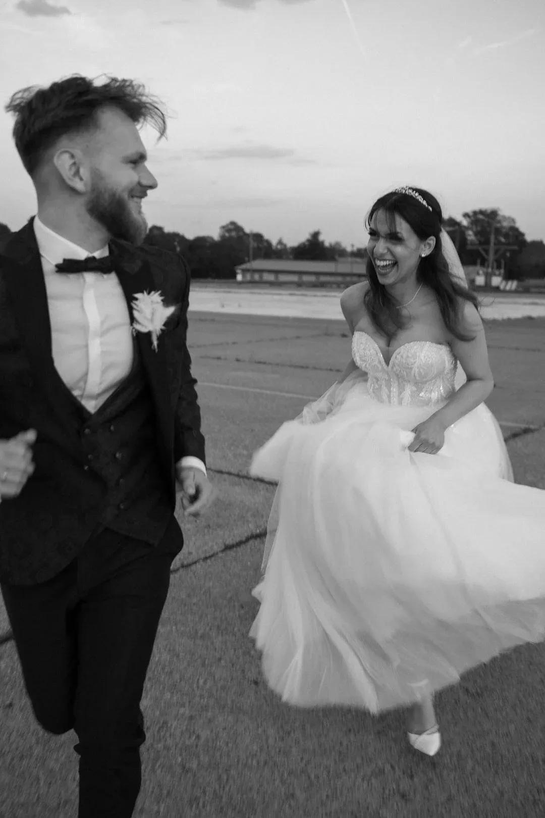 Brautpaar lacht, Kleid fliegt im Wind