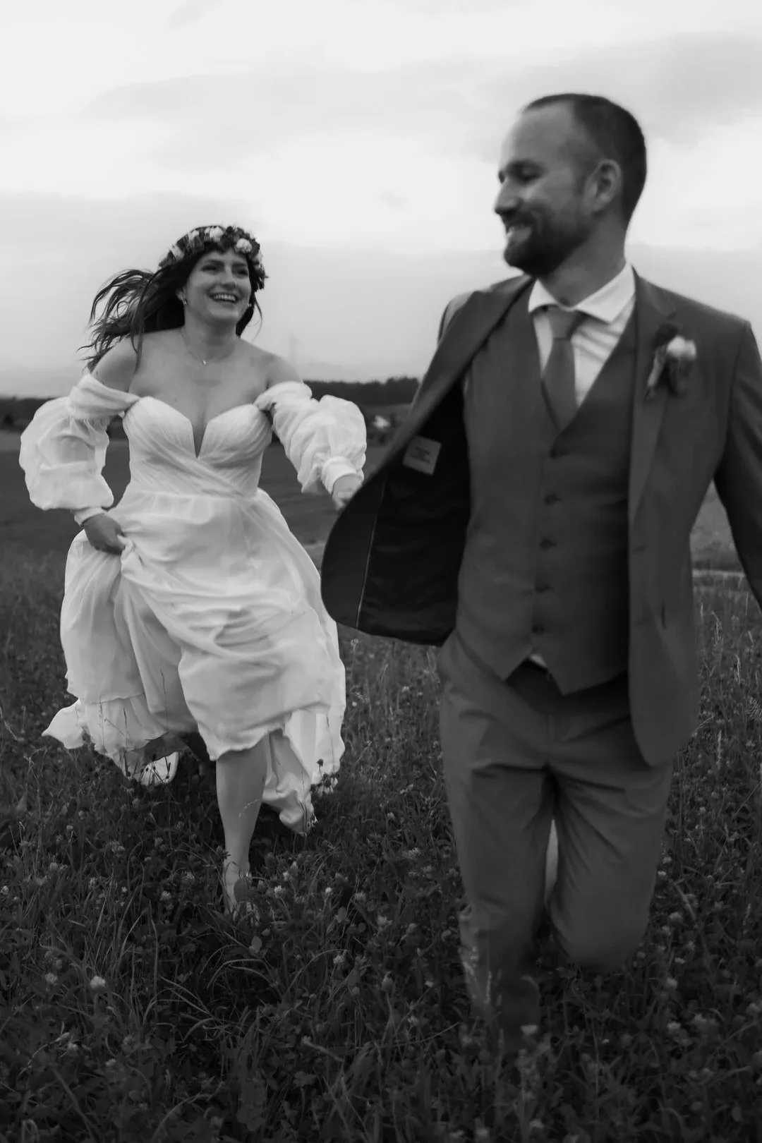 Brautpaar läuft lachend über die Wiese